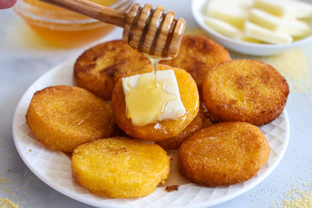 Sul de Água Quente de Pão em um prato com manteiga e mel a ser regados, e de mel e de manteiga no fundo.