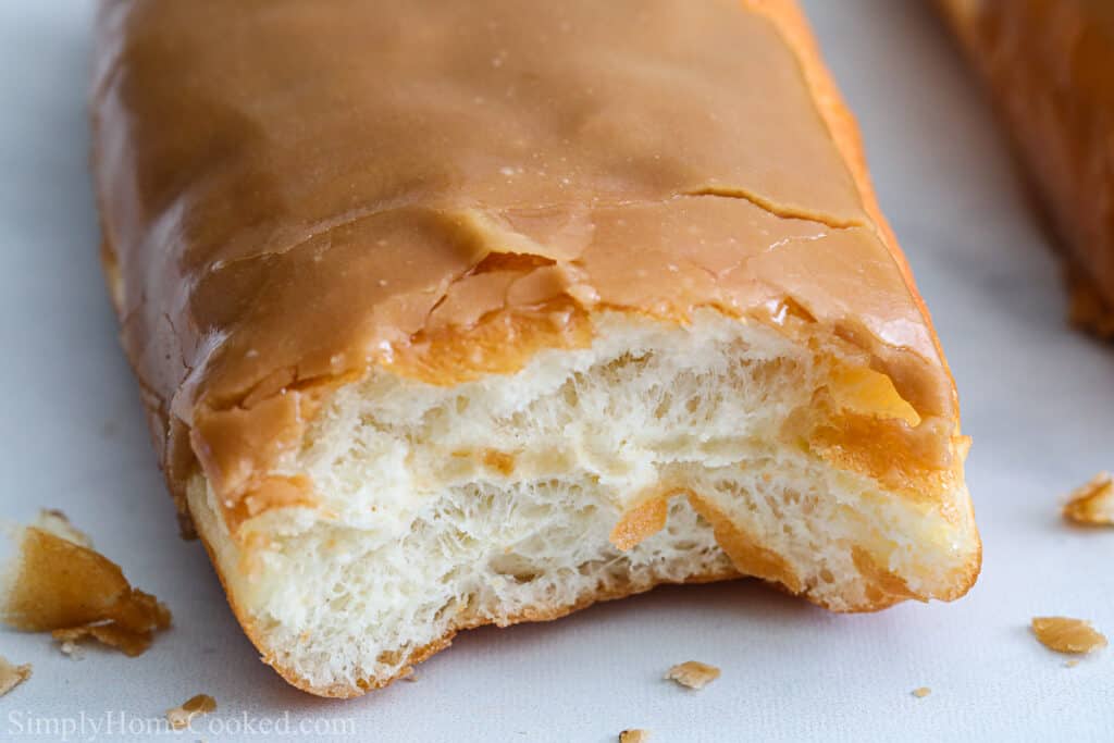 Maple Donut Bar from Scratch missing a bite on a white background with crumbs.