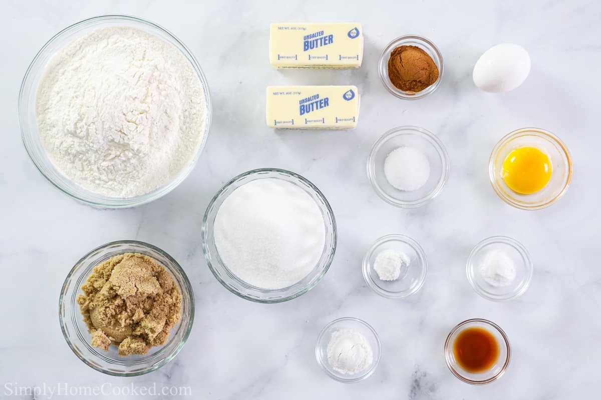 Ingredients for Soft Snickerdoodle Cookies, including flour, sugar, brown sugar, butter, cinnamon, eggs, baking powder, baking soda, salt, cream of tartar, and vanilla on a white background.