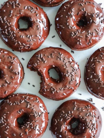 Chocolate Donuts covered in sprinkles, one missing a bite