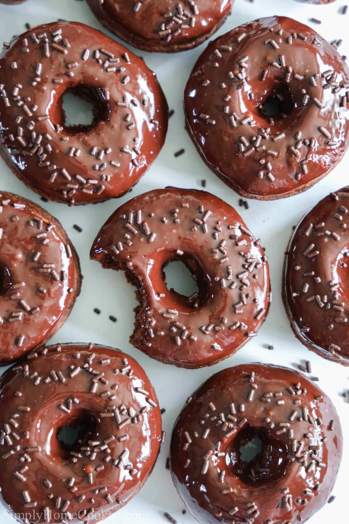 Chocolate Donuts covered in sprinkles, one missing a bite
