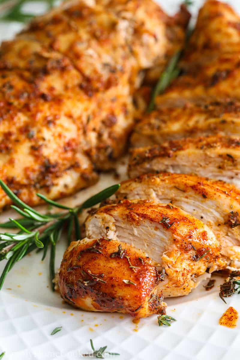 Close up of Juicy Air Fryer Chicken Breast sliced and garnished with rosemary.