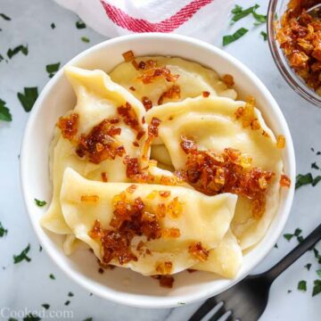 Overhead picture of a white bowl with pierogi and caramelized onions