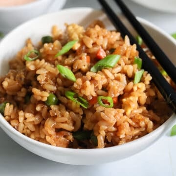 Close up of a bowl of Hibachi Fried Rice with black chopsticks on the side.