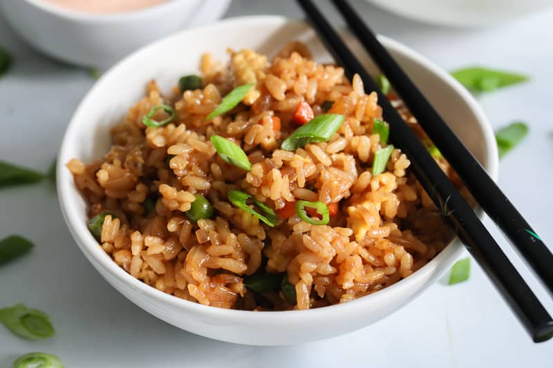 Close up of a bowl of Hibachi Fried Rice with black chopsticks on the side.