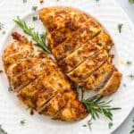 Juicy Air Fryer Chicken Breast on a white plate with rosemary garnish.