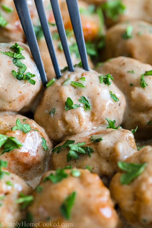 Closeup of a fork piercing a Swedish Meatball with parsley sprinkled on top