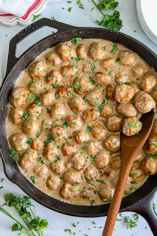 Skillet with Swedish Meatballs and a wooden spoon in it, parsley sprinkled on top.