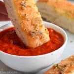 close up image of a breadstick being dipped in marinara sauce
