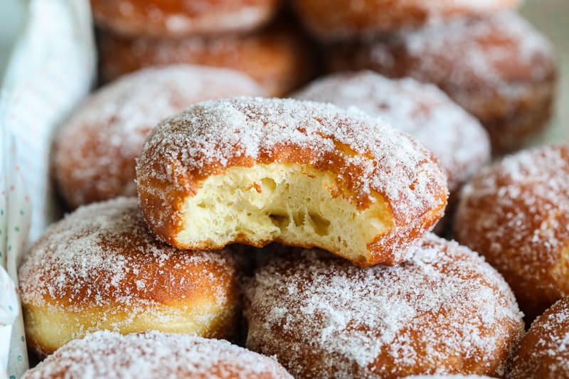 Perfect Sugar Donuts with one on top missing a bite. 