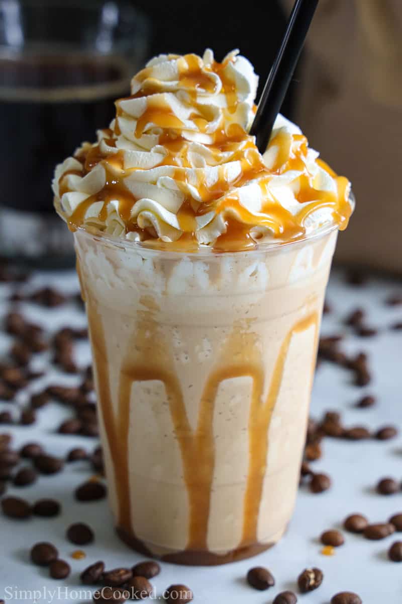 Caramel Frappuccino with a whipped cream and caramel sauce and a straw.