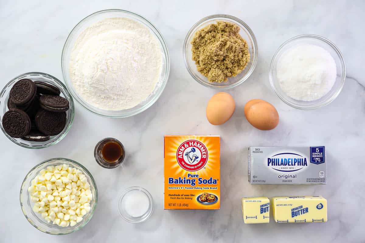 Ingredients for Cookies and Cream Cookies, including Oreos, white chocolate chips, flour, sugar, brown sugar, vanilla, eggs, cream cheese, salt, baking soda, and butter.