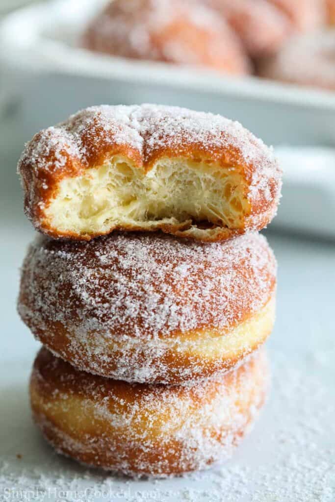 a stack of fried sugar donuts with one bitten into