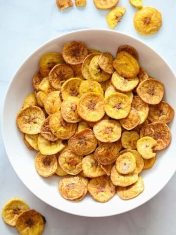 Bowl of Baked Plantain Chips with a few scattered nearby.