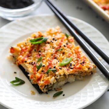 Easy Sushi Bake on a white plate with chopsticks, and a bowl of crumbled nori in the background.