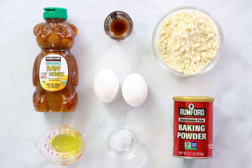 Ingredients for Almond flour pancakes, including honey, blanched almond flour, baking powder, salt, eggs, oil, and vanilla extract.