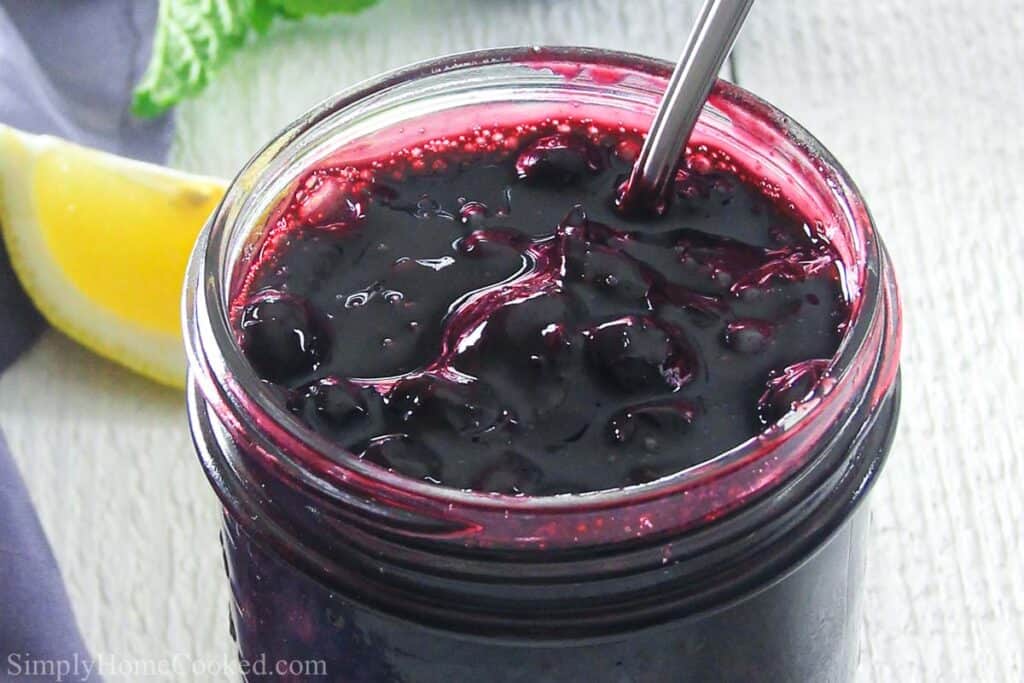 Jar of Blueberry Pie Filling with a spoon inside.