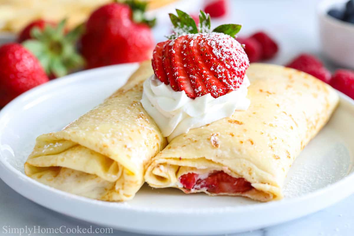 Folded crepes stuffed with whipped cream and strawberries, then add more