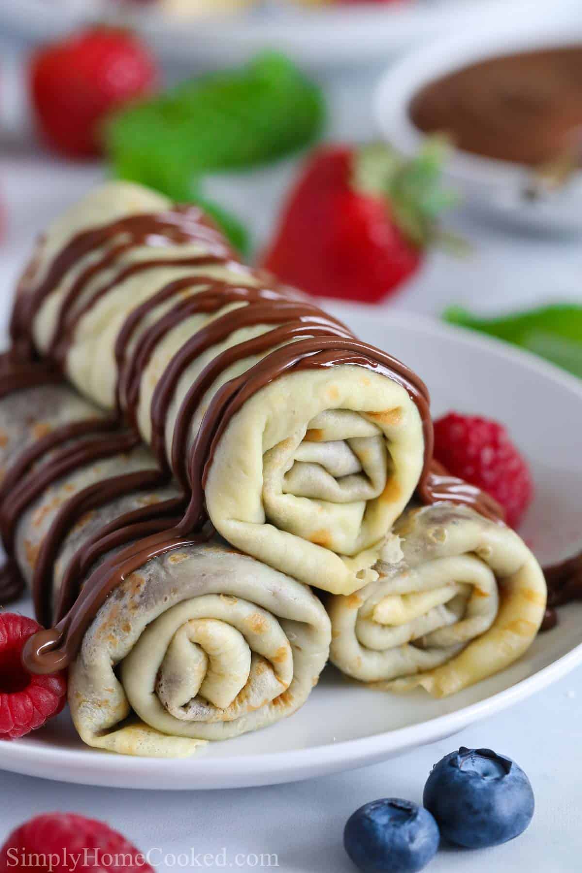 Rolled crepes stacked and drizzled with chocolate sauce