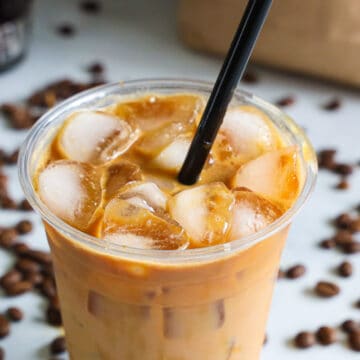 horizontal image of iced caramel macchiato with ice at the top of the cup