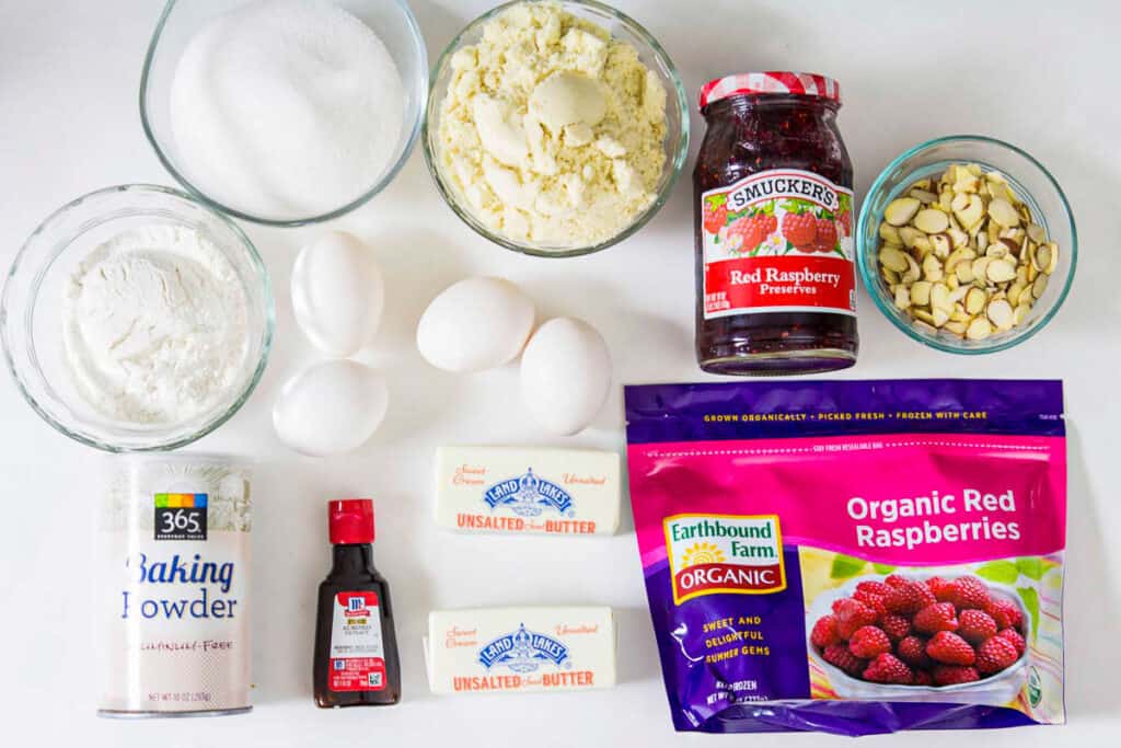 Ingredients for the raspberry frangipane filling for a Bakewell Tart, including butter, sugar, raspberry jam, almond flour, all-purpose flour, baking powder, frozen raspberries, and sliced almonds.