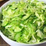 Cabbage Cucumber Salad in a white bowl with fresh dill nearby.