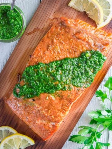 Vertical image of Cedar Plank Salmon with chimichurri sauce on top