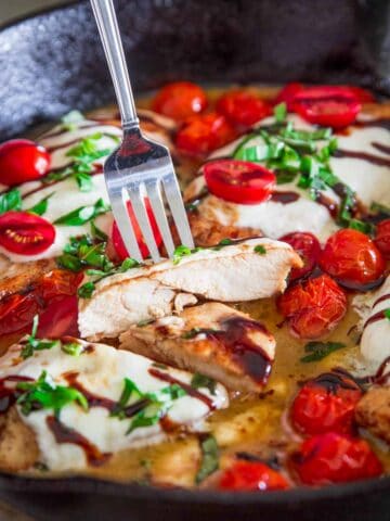 Chicken Caprese in a cast iron skillet with a fork