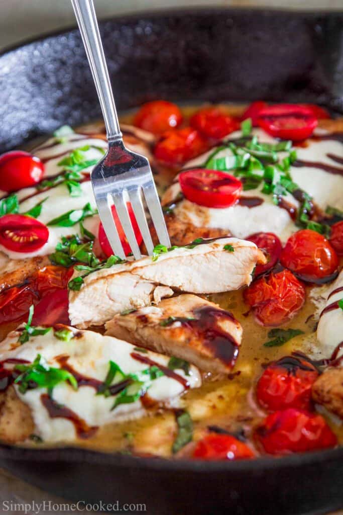 Chicken Caprese in a cast iron skillet with a fork