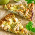 Slices of Chicken Pesto Pizza with pesto and basil nearby