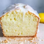 low angle image of a lemon pound cake on a wooden cutting board that has one side sliced off