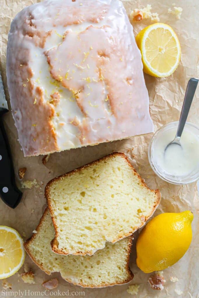 overhead image of iced lemon loaf sliced with lemon around it
