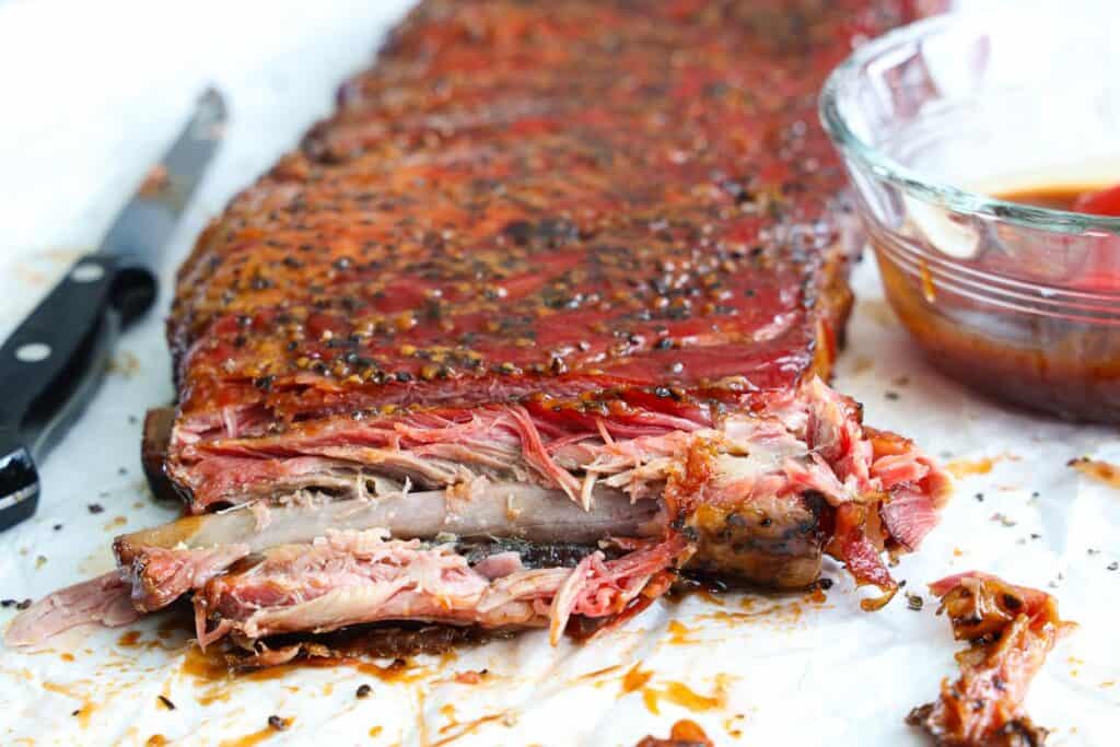 Slab of Smoked Ribs with a knife and barbecue sauce