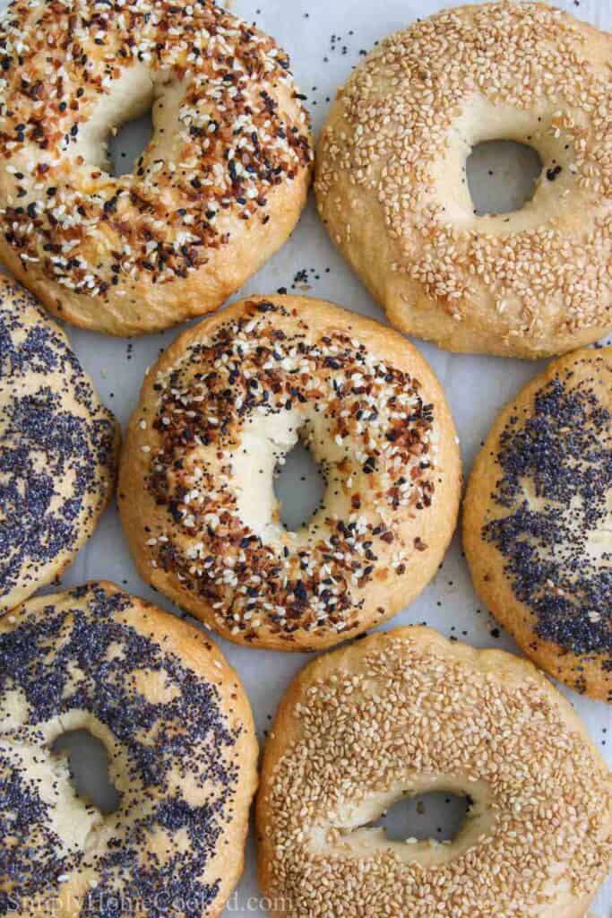 overhead image of a variety of sourdough bagels on a sheet of parchment paper