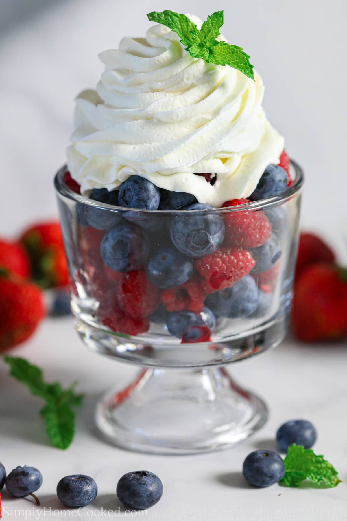 Vertical image of cup of fresh berries with Chantilly Cream on top