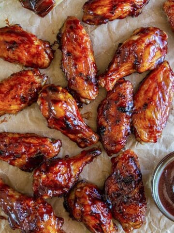 overhead image of grilled bbq chicken wings on a sheet of brown parchment paper