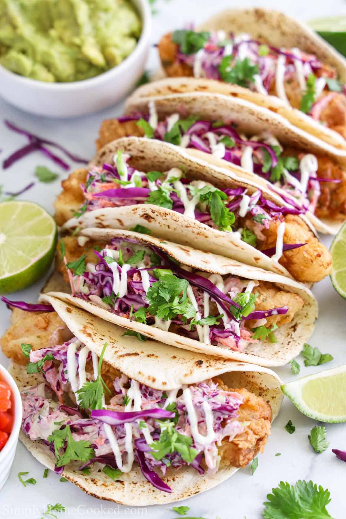 Row of Fish Tacos with limes on the side