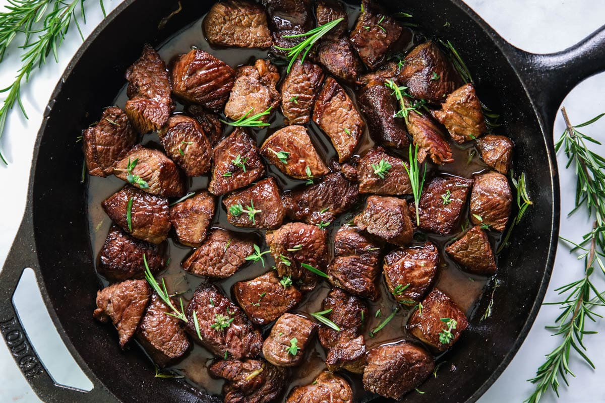 Garlic Butter Steak Bites in a cast iron pan, rosemary sprigs on the side.