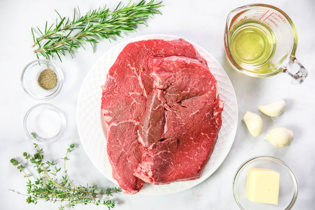 Ingredients for Garlic Herb Steak Bites, including ribeye steak, avocado oil, salt, pepper, butter, garlic, thyme, rosemary, and oregano.