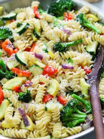 Vertical image of Pasta Primavera in a pan with a wooden spoon