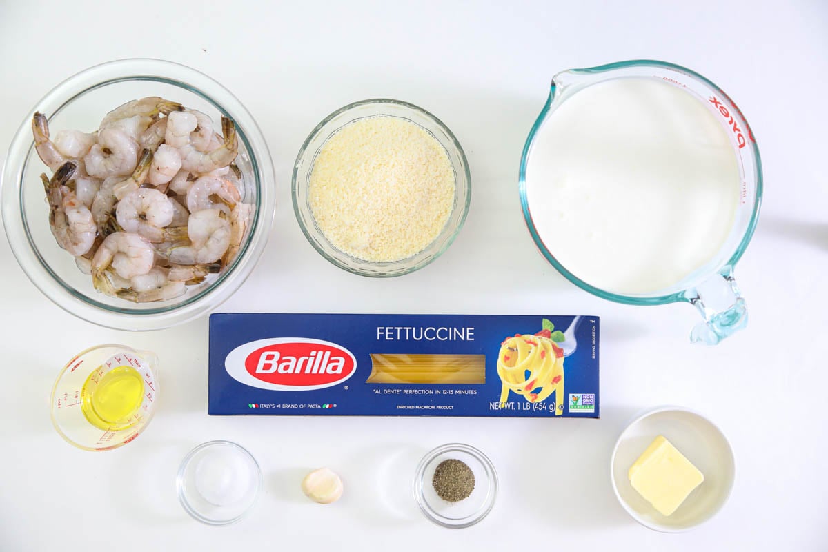 Ingredients for Shrimp Alfredo Pasta, including pasta, shrimp, cream, butter, oil, Parmesan cheese, salt, pepper, and garlic.