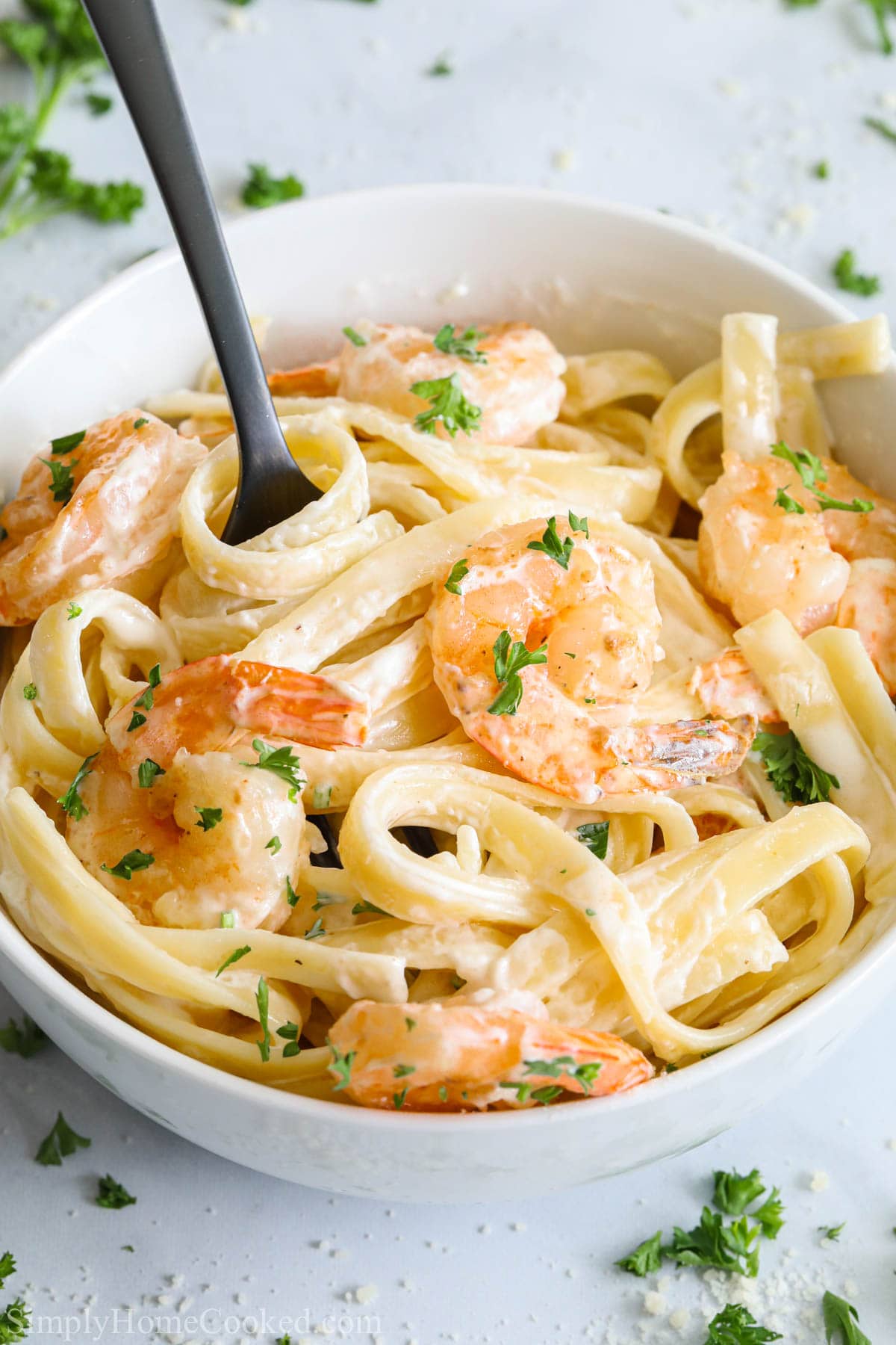 Vertical image of fork in a bowl of Shrimp Alfredo pasta