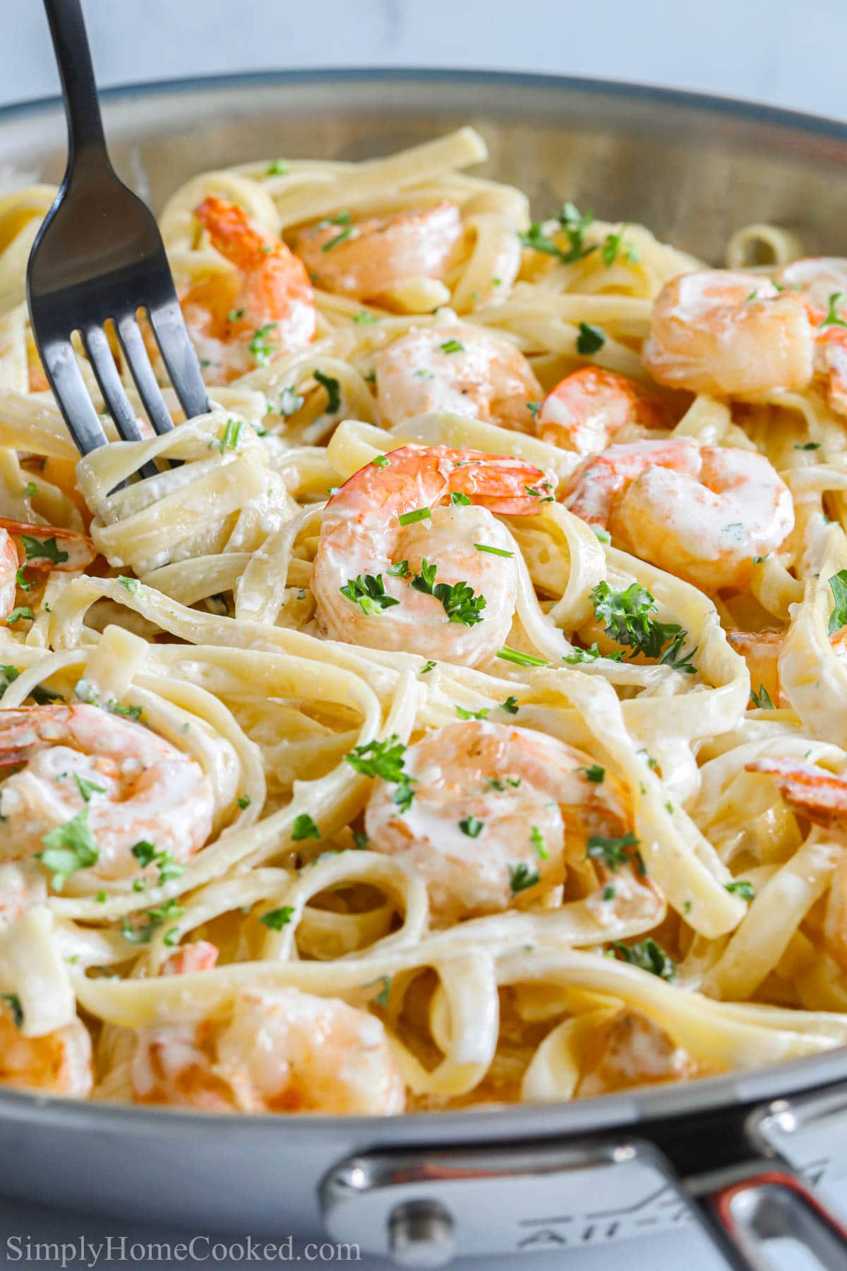 Vertical image of Shrimp Alfredo Pasta in a pan with a fork