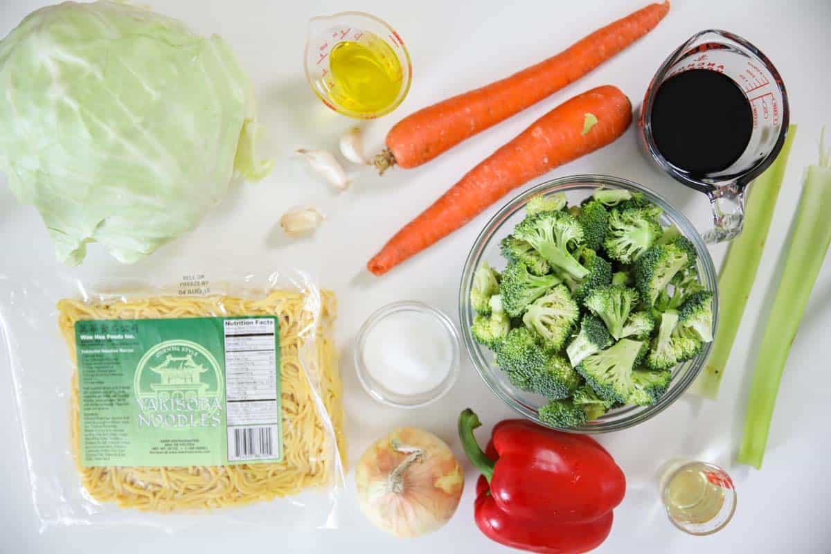 Ingredients for Chow Mein, including Garlic cloves, Celery, Carrots, Onion, Cabbage, Broccoli, and Red bell pepper, rice vinegar, soy sauce, sugar, yakisoba noodles, and oil.