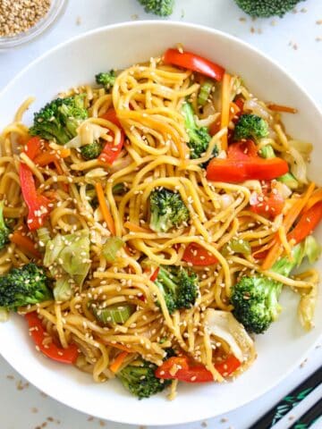 Vertical image of a plate of Chow Mein with sesame seeds sprinkled on top