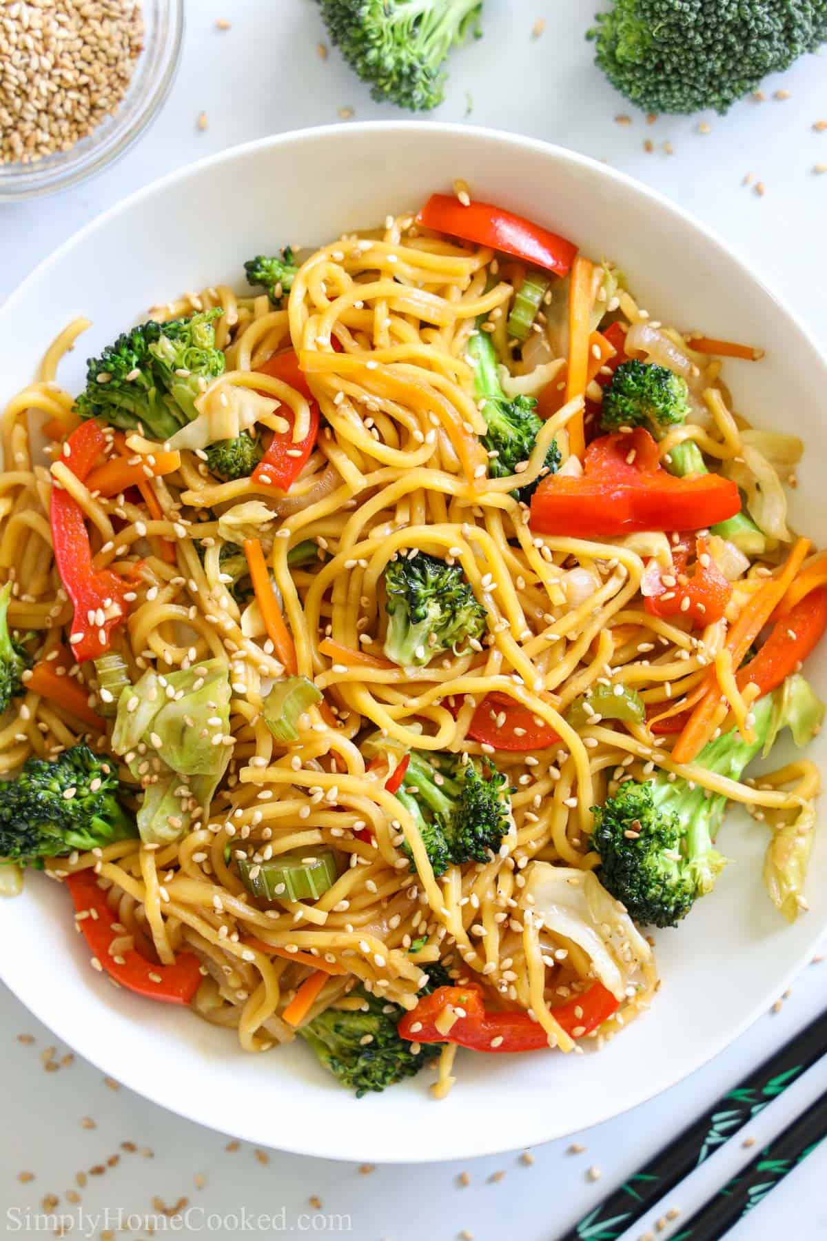 Vertical image of a plate of Chow Mein with sesame seeds sprinkled on top 