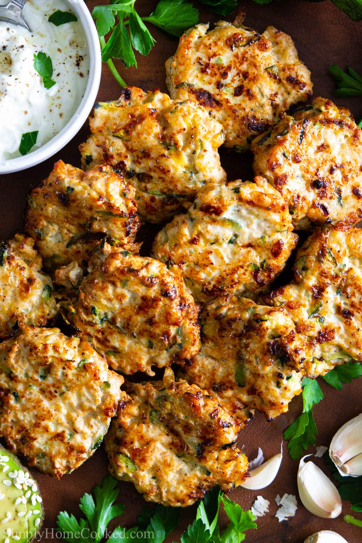Vertical image of Chicken Fritters with Zucchini with sauce nearby