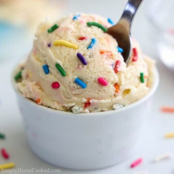 close up image of edible sugar cookie dough in a white bowl with rainbow sprinkles on top