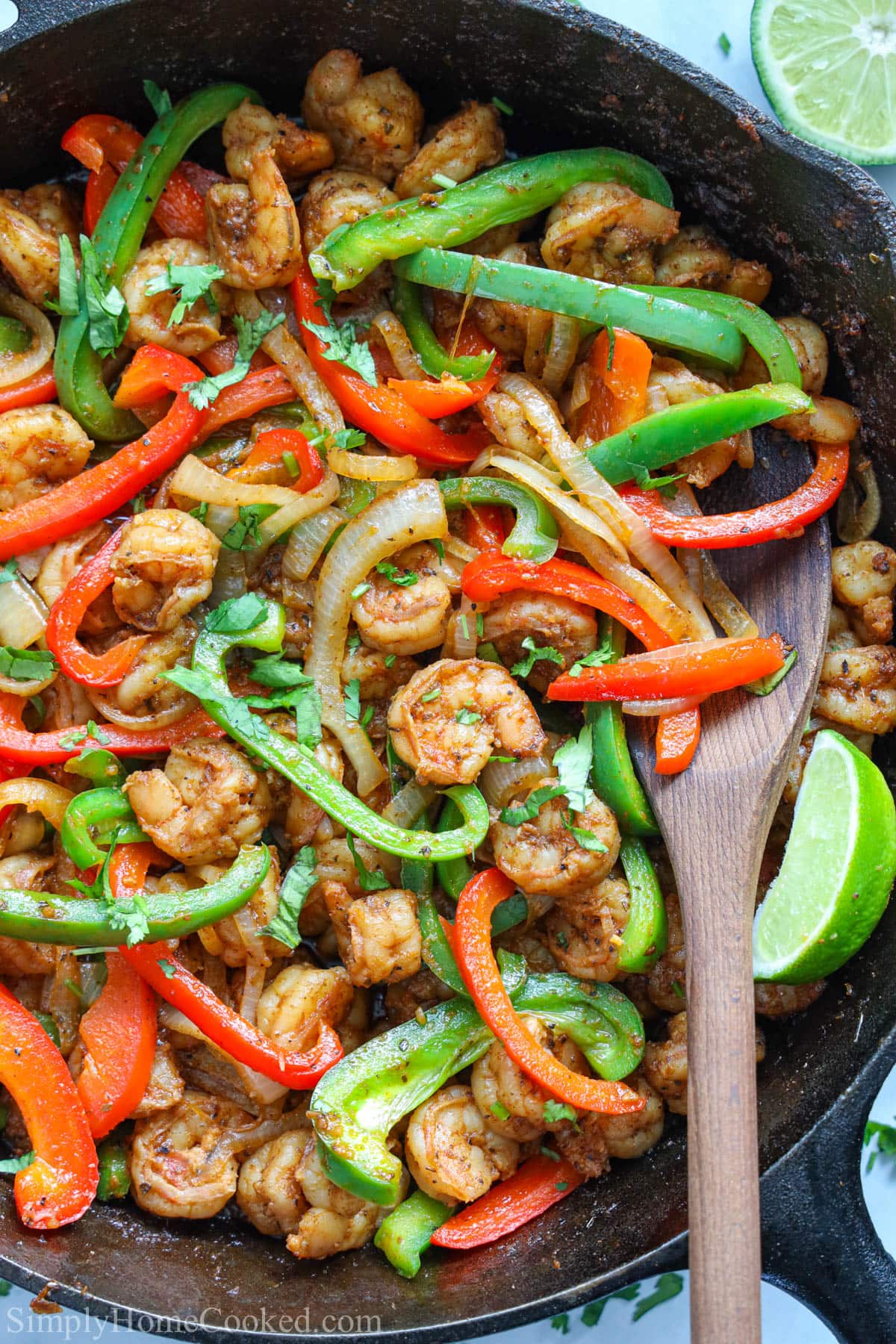 Vertical close up of Shrimp Fajitas in a pan with a wooden spoon
