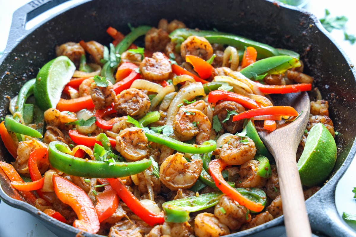 Horizontal of Shrimp Fajitas in a pan with a wooden spoon